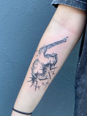 Black and gray tattoo featuring chain, ball, and morning star motifs on forearm by artist José.