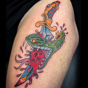 Get inked with a classic traditional snake and dagger tattoo on your upper leg by the talented artist Carlos Zucato.