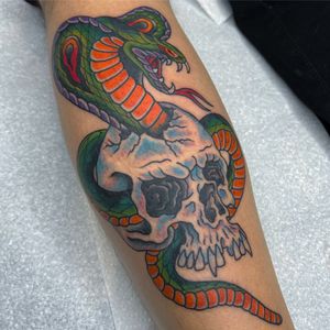 Get inked with a striking traditional tattoo design featuring a snake and skull by the talented artist Carlos Zucato.
