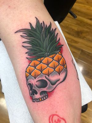 Unique lower leg tattoo by artist Carlos Zucato featuring a traditional style skull and pineapple motif.