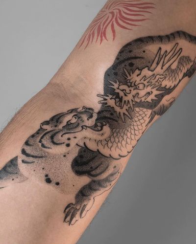 Stunning illustrative arm tattoo by FKM TATTOO featuring a fierce tiger and powerful dragon motif.