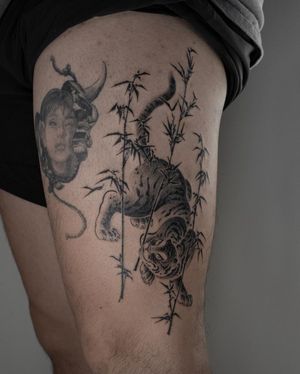 Experience the power and beauty of a Japanese-style black and gray tiger and flower tattoo on your upper leg by FKM TATTOO.