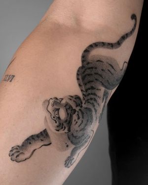 Get a fierce and elegant Japanese tiger tattoo on your forearm by FKM TATTOO. This black and gray illustrative design will make a statement.
