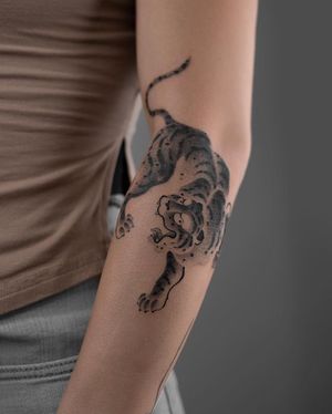 Capture the fierce power of a tiger with this black and gray Japanese style forearm tattoo by FKM TATTOO.