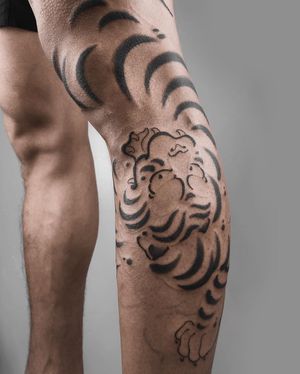 Beautiful black and gray tiger tattoo on the lower leg by FKM TATTOO, blending traditional Japanese motifs with modern blackwork.