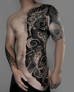 Transform your chest with a bold blackwork Japanese tattoo featuring a fierce dragon, skull, and intricate patterns by FKM TATTOO.