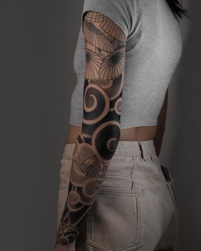 Impressive black and gray Japanese sleeve tattoo featuring a majestic crane, intricate patterns, clouds, fans, and umbrellas by FKM TATTOO.