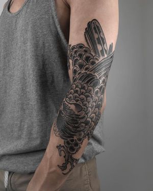 Get inked with a stunning black and gray illustrative raven design by FKM TATTOO on your arm. Embrace the mystique and beauty of this bird motif.