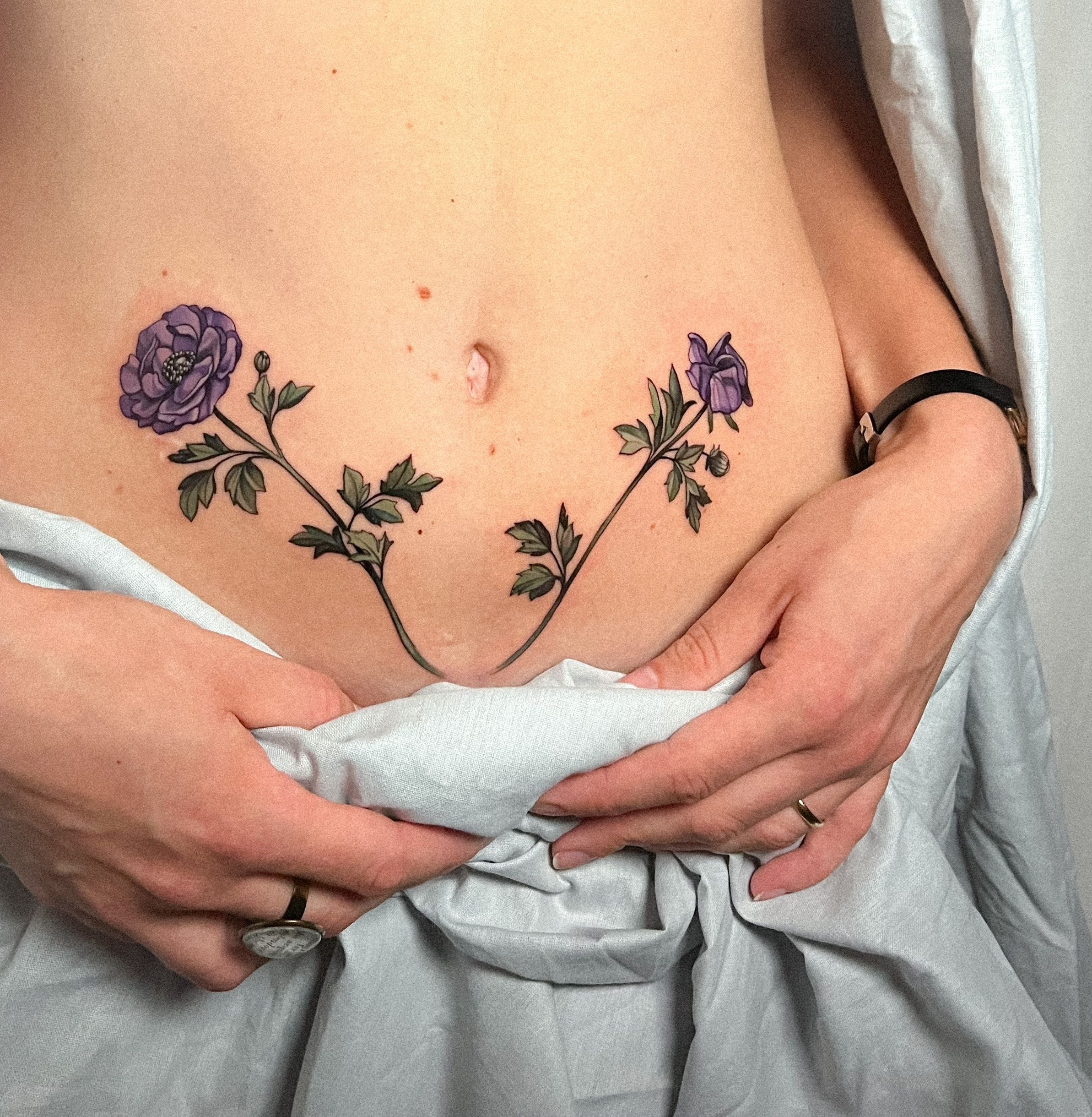 Woman in underwear showing Caesarean scar with flowers tattoo stock photo