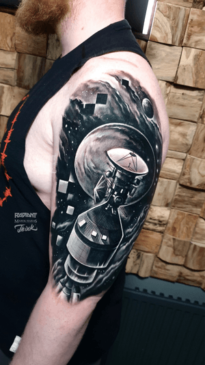 Get a stunning black and gray realism tattoo of a moon and satellite on your upper arm by Marek Unfamous Haras.