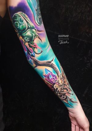 Get inspired by Marek Unfamous Haras' new school style tattoo featuring vibrant crystals and a bold beetle motif on your sleeve.
