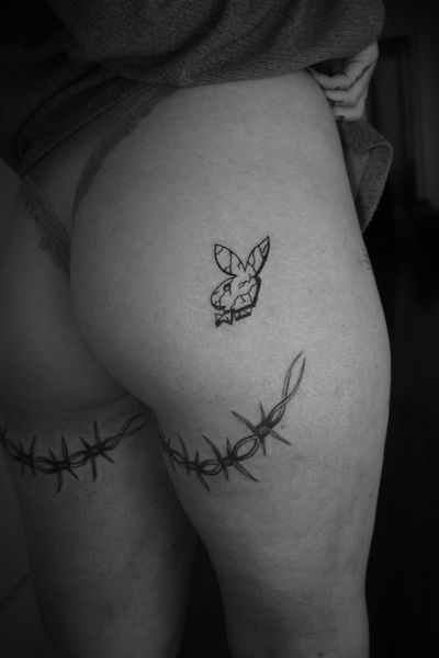 Get a sexy and sophisticated playboy bunny thigh tattoo featuring delicate fine line art by the talented artist Jeff Huet.