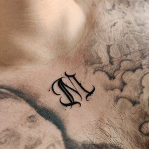 Mary Shalla's delicate and stylish letter tattoo on the chest. Perfect for a subtle and meaningful touch.