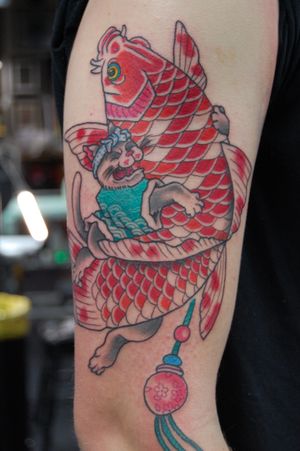 Experience the beauty of Japanese art with this stunning upper arm tattoo featuring a cat and fish design by talented artist Bananajims.