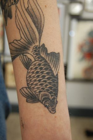 Experience the beauty of black and gray Japanese koi fish tattooed by Bananajims on your arm. Symbolizing strength and perseverance, this design is sure to make a statement.
