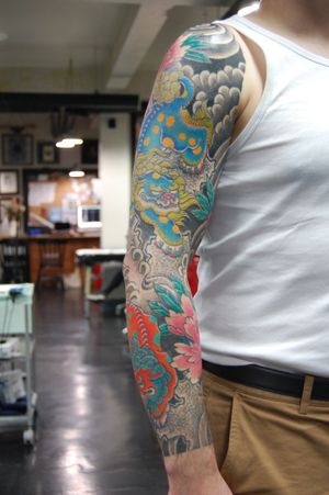 Exquisite Japanese sleeve tattoo featuring a beautiful flower and fierce foo dog design by the talented artist Bananajims.