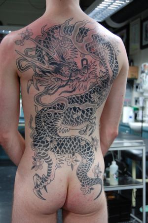 Epic back tattoo featuring a fierce dragon and beautiful flower, masterfully inked by Bananajims in traditional Japanese style.