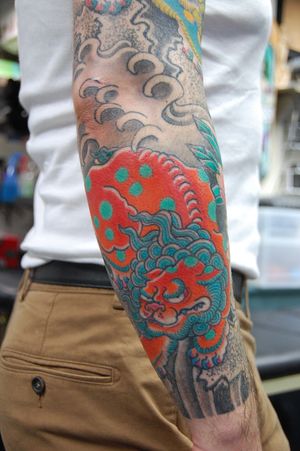 Impressively detailed foo dog tattoo designed by Bananajims, perfect for forearm placement and lovers of Japanese art.