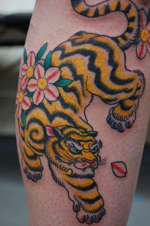 Stunning Japanese-style tattoo featuring a fierce tiger and delicate flower, expertly done by artist Bananajims on the lower leg.