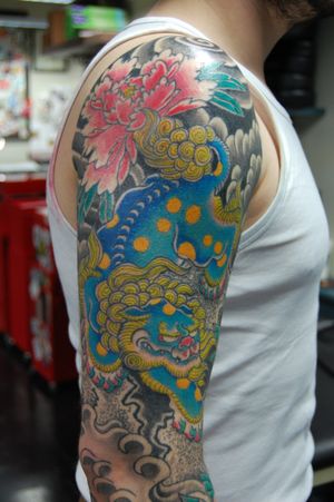 Get a stunning Japanese upper arm tattoo featuring a beautiful flower and fierce foo dog by Bananajims.