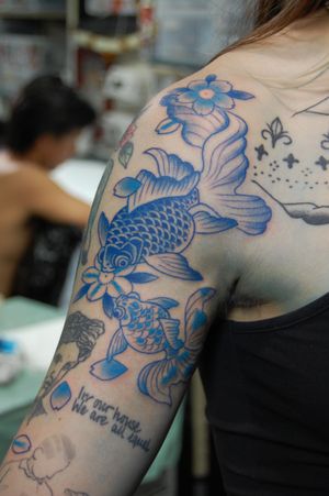 Exquisite japanese style upper arm tattoo featuring a beautiful koi fish and delicately detailed lotus flower by renowned artist Bananajims.