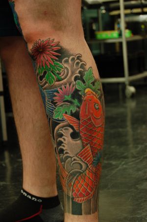 Experience the beauty of traditional Japanese art with this stunning koi fish and waves tattoo by Bananajims on your lower leg.