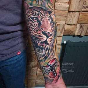 Vibrant new school tattoo featuring a realistic leopard and beetle design on the forearm by Marek Unfamous Haras.