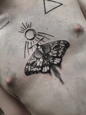 Victor Martin's black and gray dotwork chest tattoo featuring a stunning sun and moth motif. A striking and unique piece of body art.