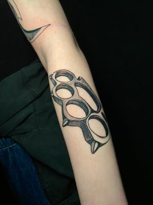 Neo-traditional meets black and gray with Victor Martin's striking brass knuckles design. Make a bold statement on your forearm with this badass tattoo.
