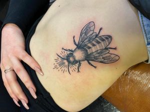 Victor Martin's intricate black & gray bee tattoo beautifully complements the curves of your ribs.