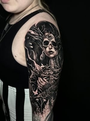 Experience Avi's haunting realism with this black and gray surreal skeleton tattoo on your upper arm.