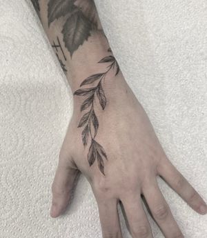 Get a stunning black and gray floral leaf tattoo on your hand, expertly designed by Federico Colantoni for a touch of elegance.