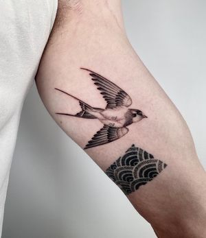 Elegant black and gray swallow tattoo on upper arm by talented artist Martin Rosenberg. Timeless design for a classic look.
