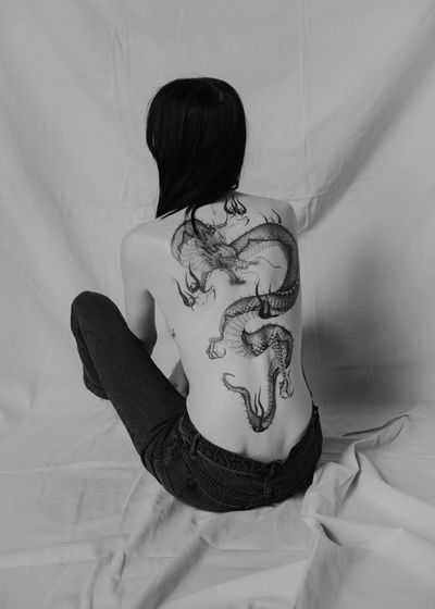 Immerse in the mythical world with this black and gray tattoo by Delphin Musquet. The powerful dragon symbolizes strength and protection.