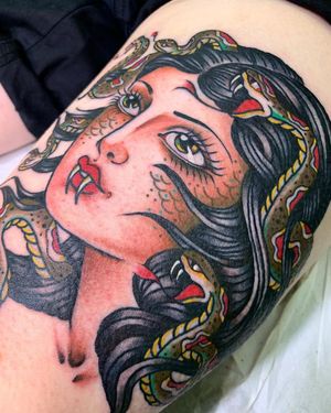 Get mesmerized by this stunning traditional Medusa tattoo on your thigh, expertly done by the talented artist Laurel.