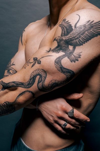 Delphin Musquet's stunning black and gray realism tattoo featuring a majestic eagle and a fierce snake on the arm.