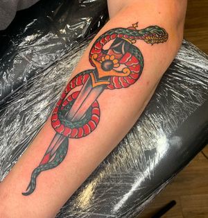 Classic design featuring a menacing snake intertwining with a sharp dagger, expertly done by Laurel on your arm.