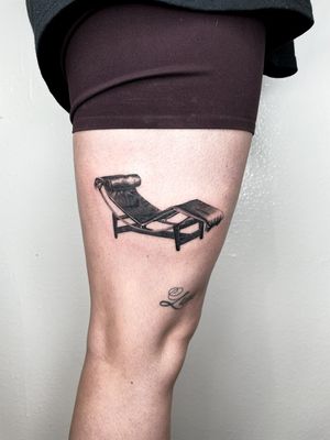 Get a stylish upper leg tattoo of a lounge chair inspired by Le Corbusier's modern designs. By artist Martin Rosenberg.