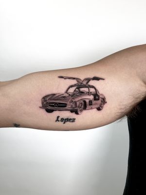 Experience the detail and precision of Martin Rosenberg's micro realism tattoo featuring a sleek Mercedes SLS on your upper arm.