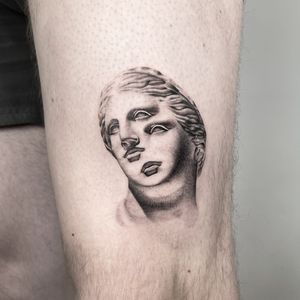 Get a stunning black and gray upper leg tattoo of a detailed statue bust portrait by Martin Rosenberg.