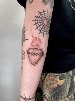 Explore Martin Rosenberg's black and gray heart design on lower arm with intricate fine line work.