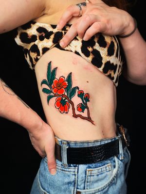 Get a vibrant new school flower tattoo on your ribs in London, GB. Stand out with this colorful and modern ink design.