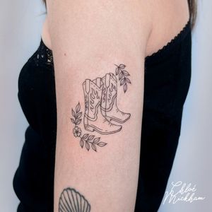 Capture the essence of the Wild West with this intricate fine line tattoo of cowboy boots by Chloe Mickham. Perfect for any cowboy or cowgirl at heart.