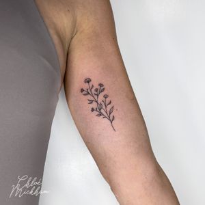 Elegant fine line tattoo featuring a beautiful flower sprig design by Chloe Mickham.