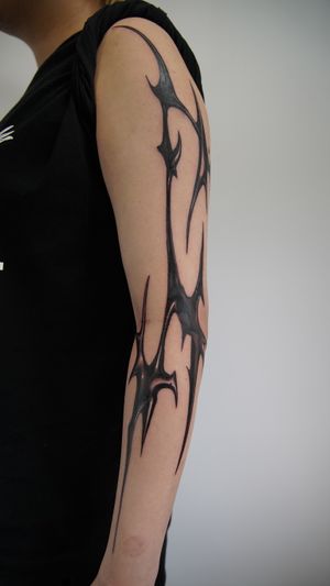 Unique blackwork design combining tribal motifs intricately inked by Jacky Yang on the arm.