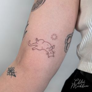 This delicate fine line tattoo by Chloe Mickham features a charming cat motif, perfect for pet lovers seeking a minimalist design.