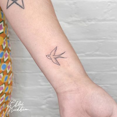 Elegant and delicate tattoo of a swallow done in fine line style by the talented artist Chloe Mickham.