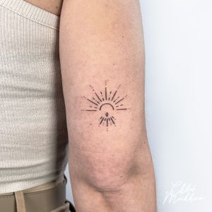 Get a beautiful and intricate fine line sun tattoo by Chloe Mickham for a subtle yet stunning look.