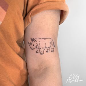 Experience the beauty of fine line and illustrative styles in this intricate rhinoceros tattoo by talented artist Chloe Mickham.