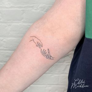 Exquisite fine line tattoo by Chloe Mickham featuring a delicate skeleton hand motif.